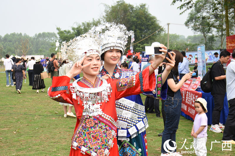 游客穿著少數(shù)民族特色服飾在景點(diǎn)打開拍照。人民網(wǎng) 王功孝攝